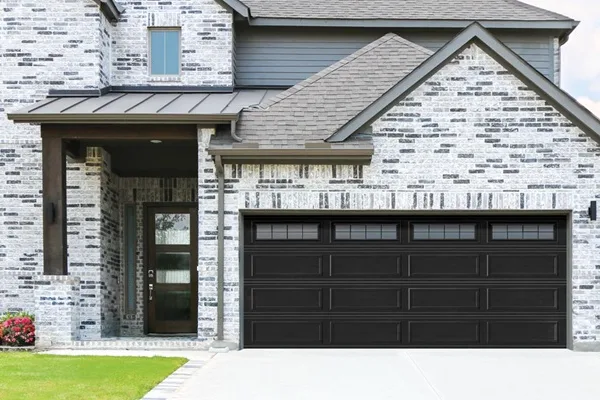 New black garage door installed on a stone and brick home